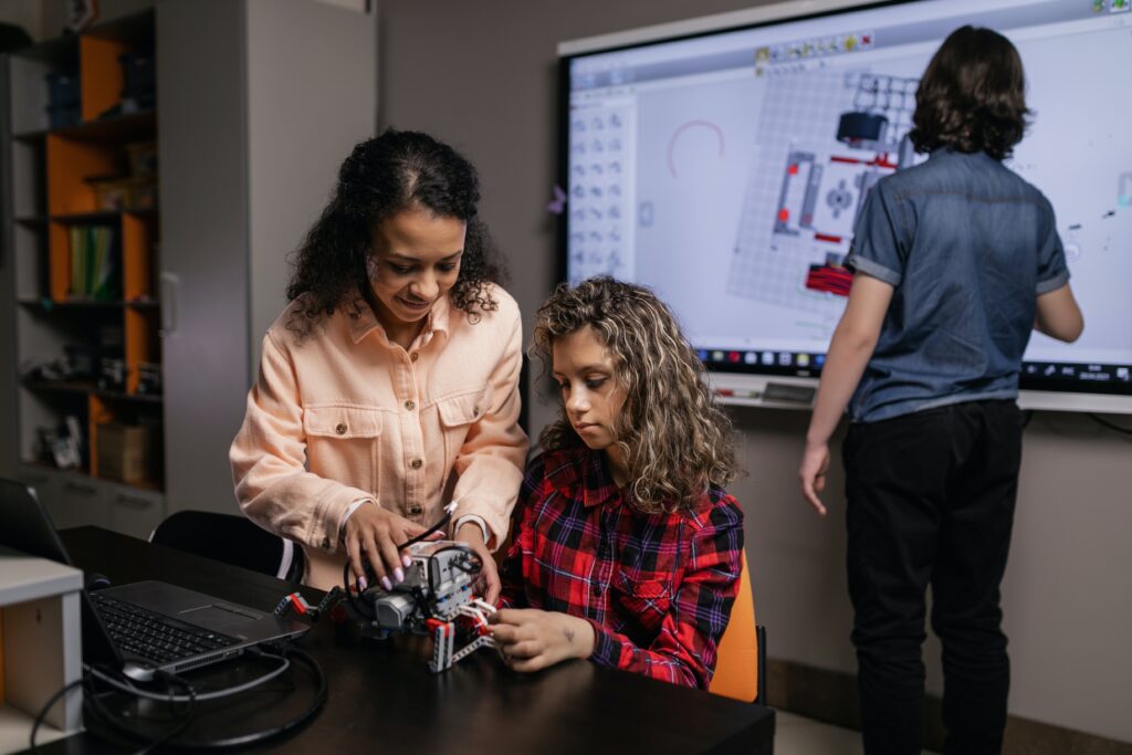 Three secondary students collaborating to design and program robotics